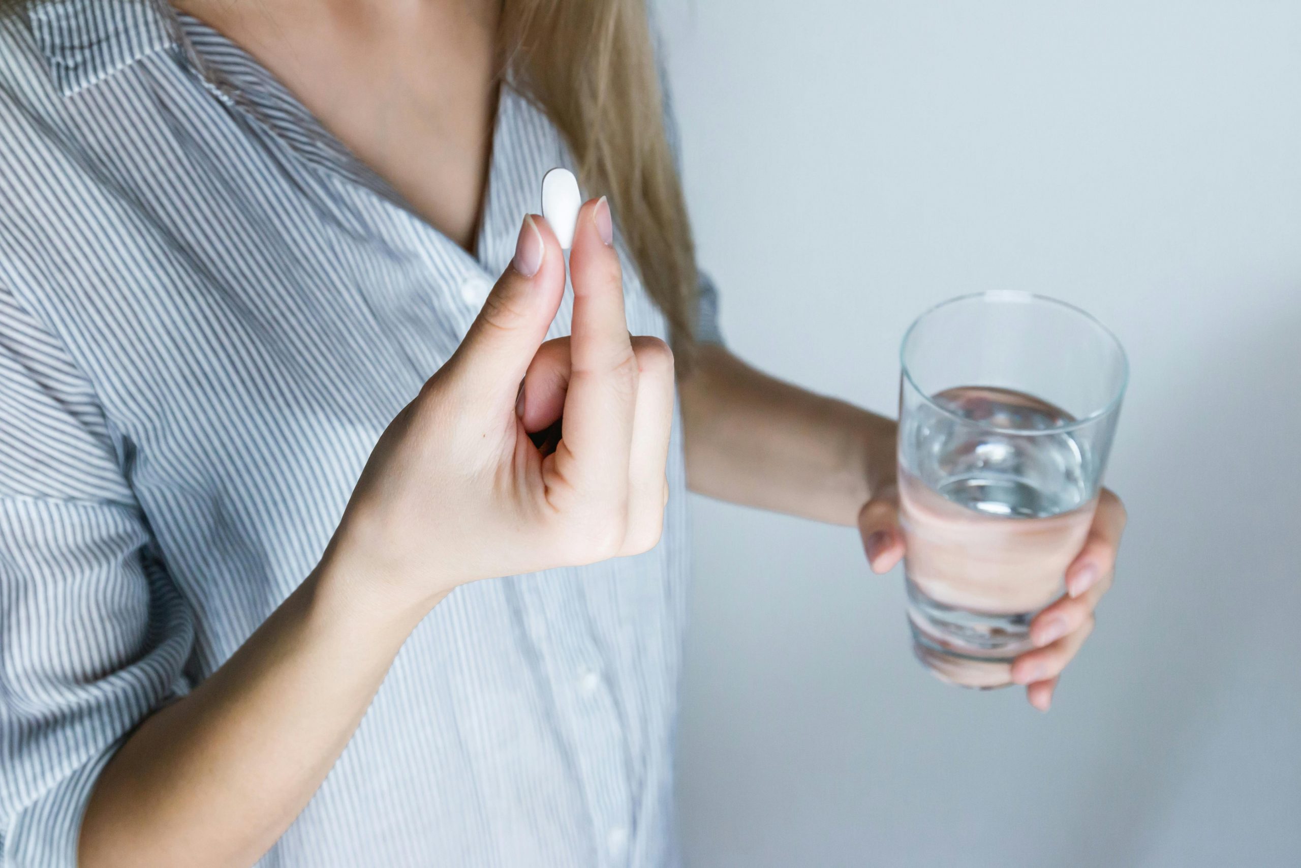 woman preparing to take a pill with a glass of water