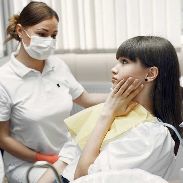 patient touching her jaw as a dentist observes