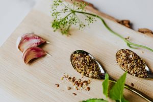 ground cloves on a spoon beside garlic on a chopping board