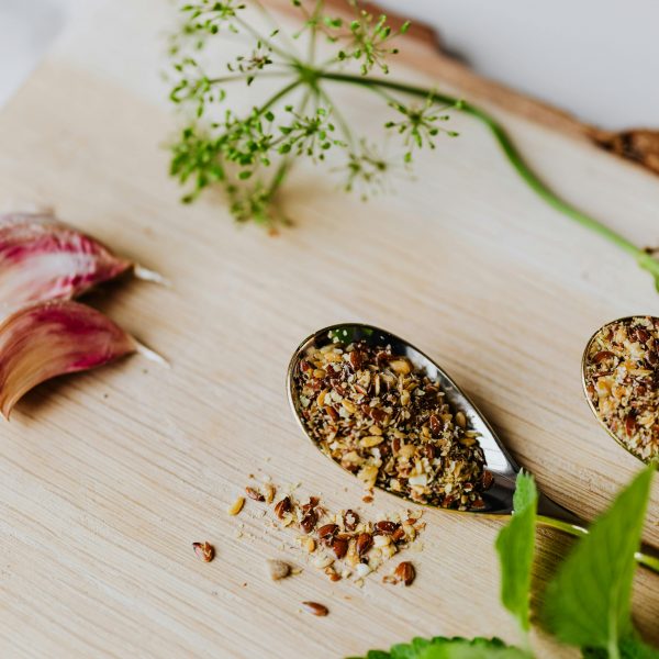 ground cloves on a spoon beside garlic on a chopping board